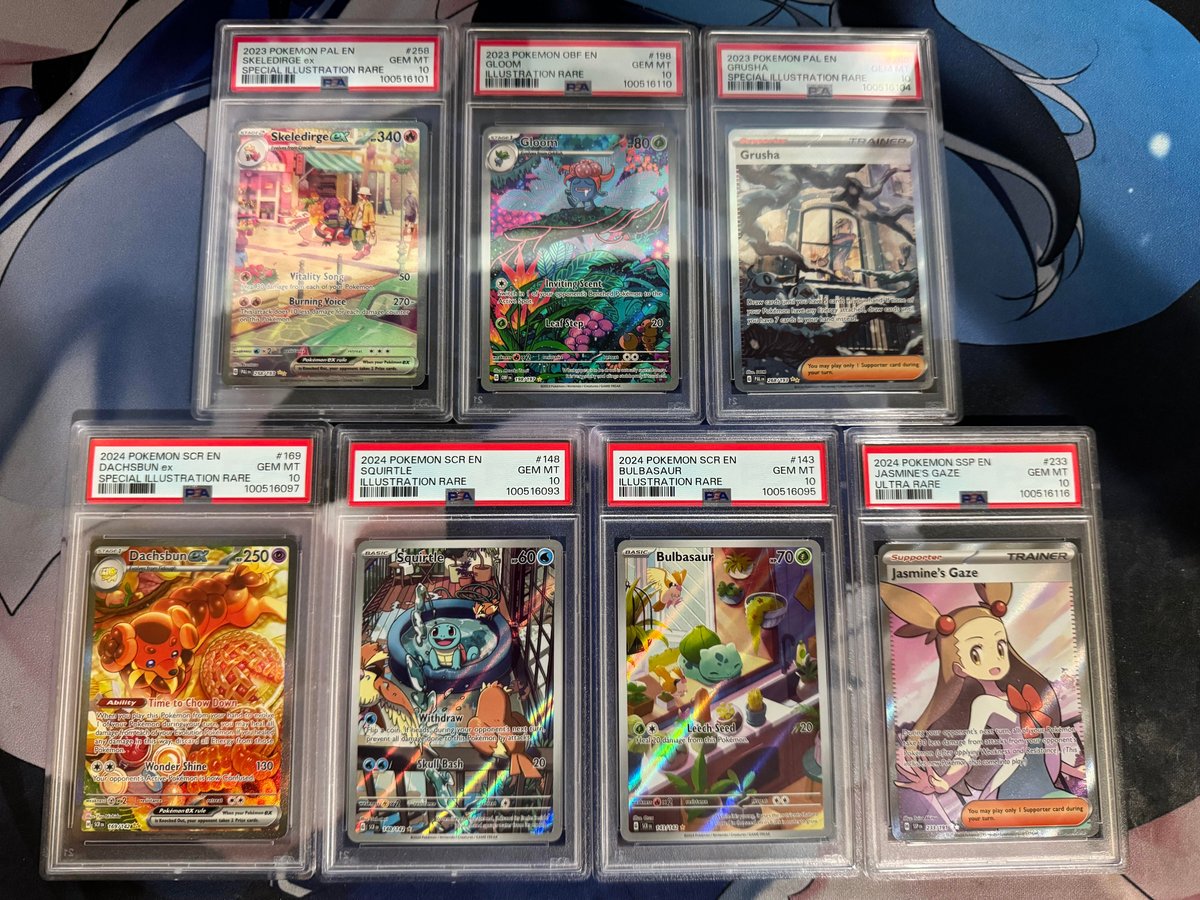 Seven PSA-graded Pokemon slabs returned from a GameStop submission, displayed on a blue surface. The haul includes modern SARs and illustration rares.
